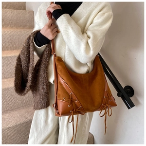 Close-up of caramel suede tote bag detail with leather drawstring and eyelet laces