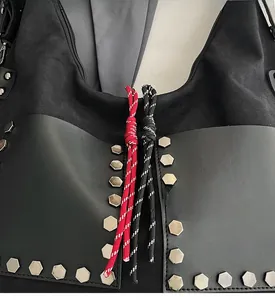 Detail of black leather bucket bag featuring silver hexagonal studs and woven drawstring
