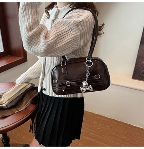 Détail d'un sac sous les aisselles en cuir brillant marron avec pendentif nœud