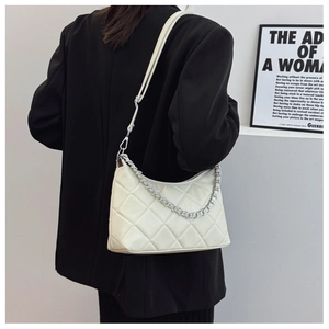 Close-up of beige quilted crossbody bag with silver chain strap and half-moon design