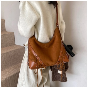 Macro detail of brown suede and leather stitching on a large vintage shoulder bag
