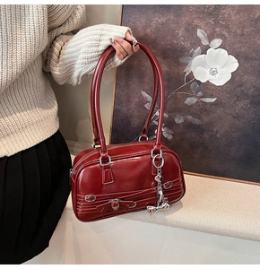 Détail du sac à main bordeaux en cuir verni avec nœud et finitions métalliques argentées