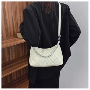 Quilted beige shoulder bag with silver chain strap shown worn by a model in a minimal room