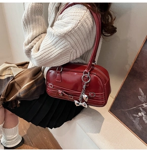 Détail du sac à main rouge foncé avec boucles argentées et pendentif en métal en cœur