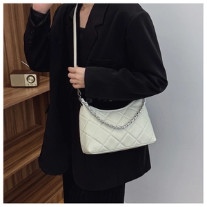 Detail view of cream white quilted crossbody bag featuring silver chain and fine stitching