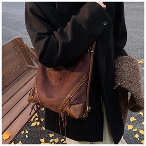 Detail of vintage brown suede hobo bag with lace-up side design worn by a model