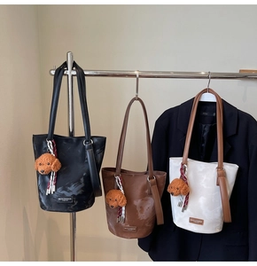 Three leather tote bags in black brown and white with plush teddy charms and ribbon