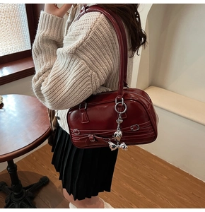 Vue détaillée du sac à main bordeaux avec boucles argentées et breloque ruban coeur