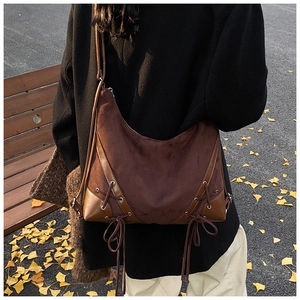 Close-up of retro brown shoulder bag showing suede texture and lace-up metal eyelet details