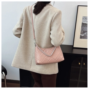 Detailed back view of pink quilted handbag with silver chain strap on model in suit