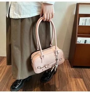 Détail d'un sac à main en cuir verni rose avec un nœud et un pendentif cœur argenté