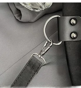 Detailed macro view of silver metal hooks and rivets on a black leather bucket bag