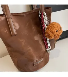 Detailed texture of brown PU leather tote bag featuring a cute plush dog pendant charm