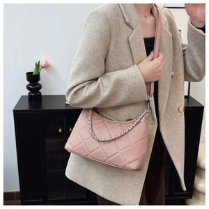 Close-up of pink quilted baguette bag with silver chain and adjustable shoulder strap