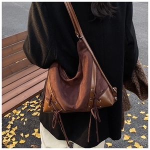 Detail of dark brown suede shoulder bag with vintage cross-lace ties on autumn backdrop
