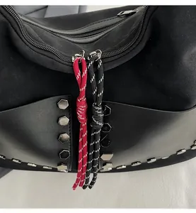 Detail of black bucket bag featuring silver hexagonal studs and dual zipper cords