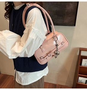 Détail d'un sac à main en cuir verni rose avec boucles en métal et pendentif en cœur