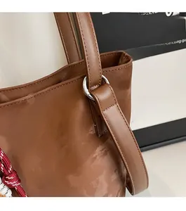 Detail of silver buckles and neat stitching on the brown leather bucket bag side