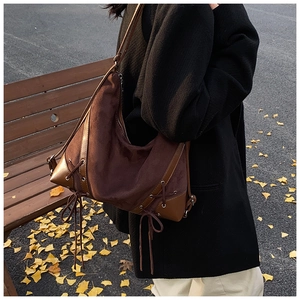 Detail of dark brown matte suede hobo bag with side lace-up knots on model
