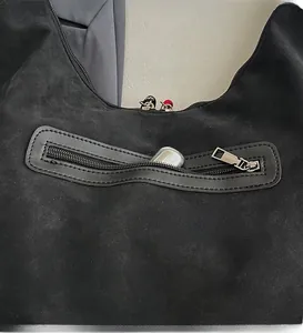 Detail of a black suede bucket bag featuring a functional back zipper pocket for small items