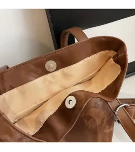 Detail view of the brown leather bucket bag featuring a magnetic buckle and inner zip pocket