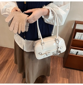 Sac à main en cuir verni blanc avec chaîne argentée tenu par une main gantée