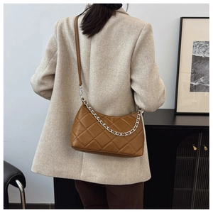 Close-up of brown quilted shoulder bag with silver chain and metal zipper details