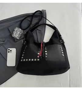 Flat lay of black hobo tote bag with silver rivets and woven tassel details