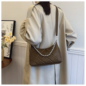 Brown quilted crossbody bag with silver chain and adjustable strap worn by model