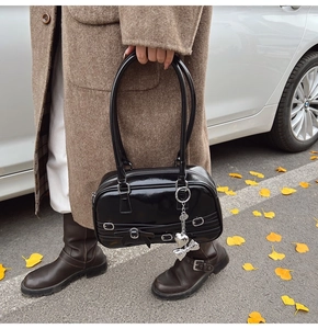 Détail du sac à épaule en cuir verni noir avec pendentif cœur et nœud décoratif