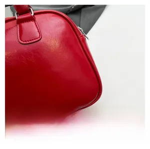 Gros plan du sac oreiller en cuir rouge brillant avec fermeture éclair argentée et plis