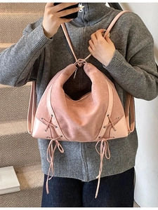 Pink suede hobo bag with patent leather trim and tassel side ties for casual style