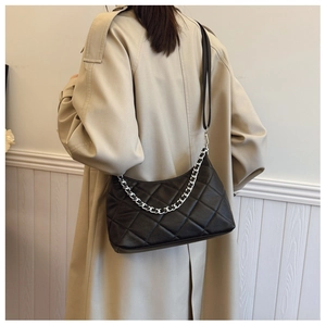 Detailed view of black quilted leather crescent bag with silver chain strap on model