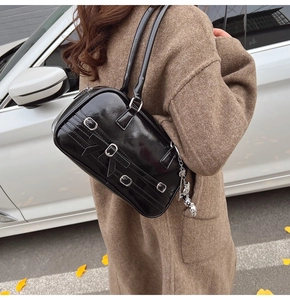 Vue détaillée du sac sous le bras en cuir verni noir avec nœud et boucles argentées