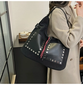 Detail of black canvas bucket bag with silver hexagonal studs and woven tassel ornament