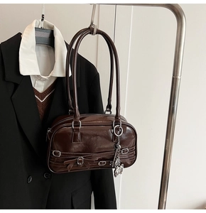 Vue détaillée d'un sac en cuir verni marron foncé avec pendentif papillon et boucles rétro