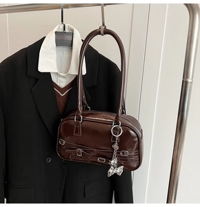 Vue détaillée du sac à main en cuir verni marron foncé avec breloque cœur argentée