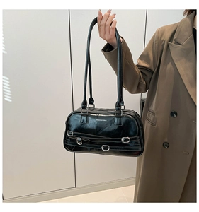 Détail du sac bandoulière noir brillant avec boucles argentées et lettrage de marque