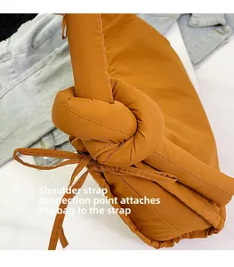 Close-up of knotted shoulder strap detail on a caramel quilted nylon puffer tote bag