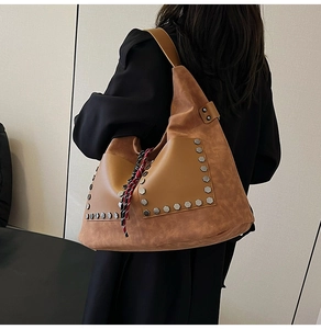 Detail of vintage brown suede tote bag featuring silver studs and colorful woven charm