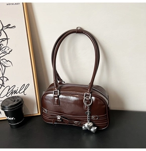 Détail d'un sac sous les aisselles marron foncé brillant avec zip et nœud décoratif