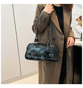 Détail du sac en cuir brillant noir avec plusieurs boucles argentées et logo de la marque