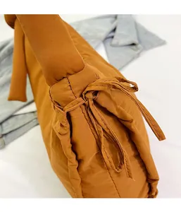 Close-up of quilted nylon shoulder bag with stylish knot detail in caramel brown