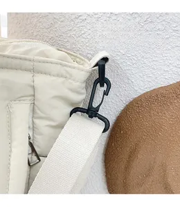 Detail des abnehmbaren schwarzen Hakens und Riemens an der cremefarbenen Stepptasche