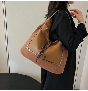 Detail of a brown bucket bag with hexagonal metal rivets and woven rope decoration