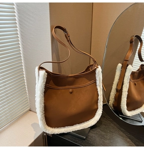 Detail of brown suede hobo bag with white faux shearling trim and adjustable shoulder strap