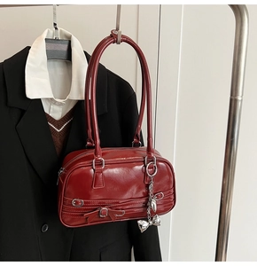 Détail du sac à bandoulière en cuir verni rouge avec nœud et breloque papillon argentée