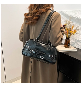 Sac bandoulière noir brillant avec boucles argentées porté par un mannequin