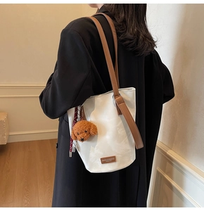 Detail of white leather tote bag with brown straps and cute teddy bear plush charm