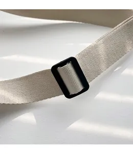 Detail eines verstellbaren beigen Schultergurts mit schwarzer Schnalle für Stofftaschen